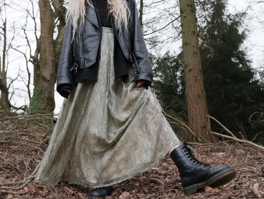 Edgy forest outfit: leather jacket, lace maxi skirt, and black combat boots, grunge street style in the woods.